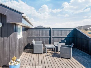 A deck with wicker furniture and a potted plant. - 4 Star Holiday Home in Hirtshals (Hirtshals)