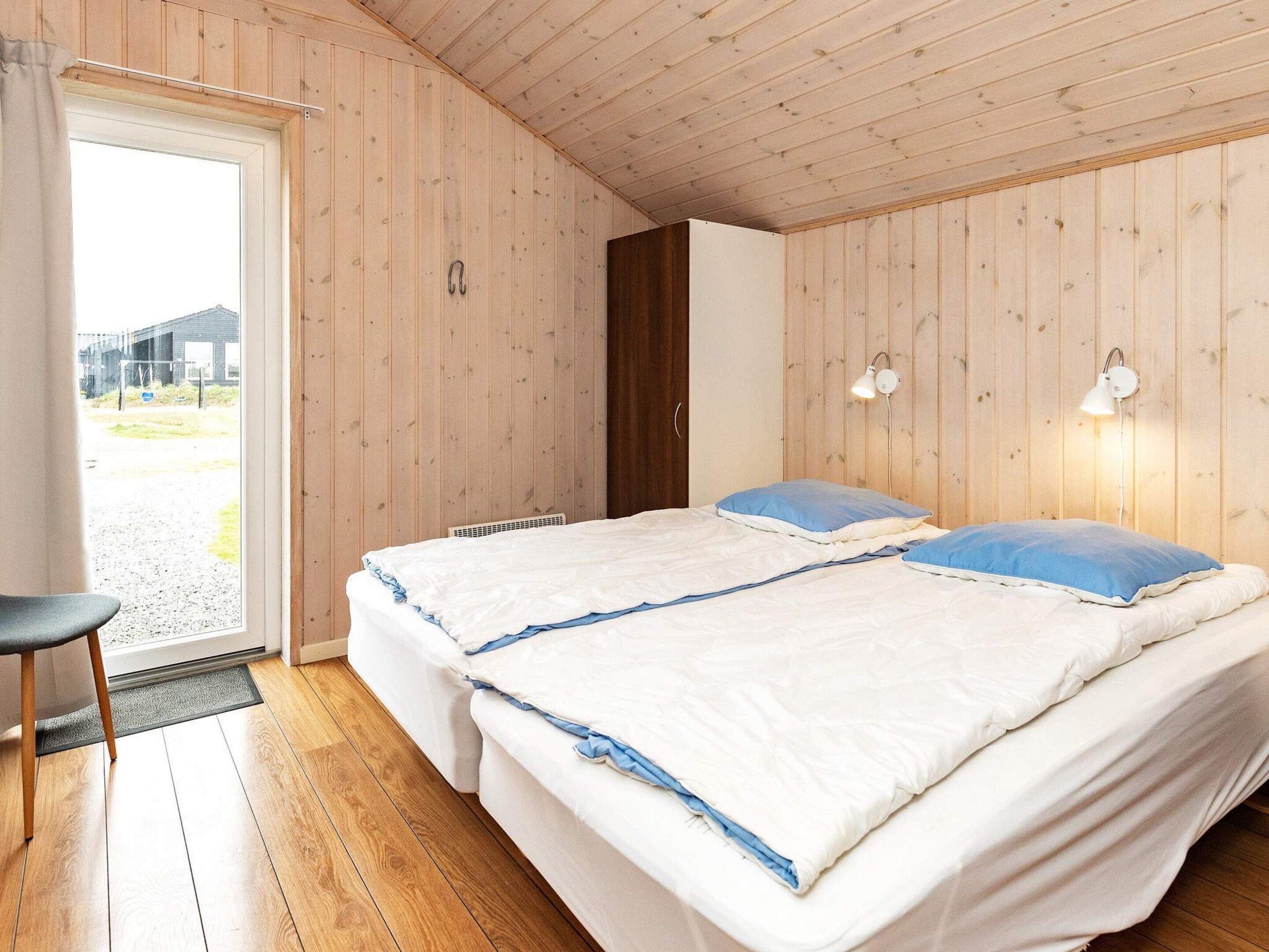 Une chambre avec deux lits, une porte, une chaise et une vue sur l’extérieur.