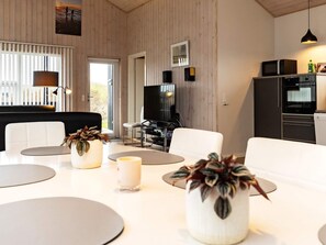 A modern living room with a television, seating area, and kitchen.