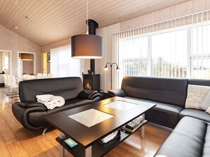 A modern living room with a sofa, a coffee table, and a fireplace. - 4 Star Holiday Home in Hirtshals (Hirtshals)