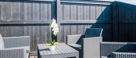 An outdoor patio with wicker furniture and a potted orchid.