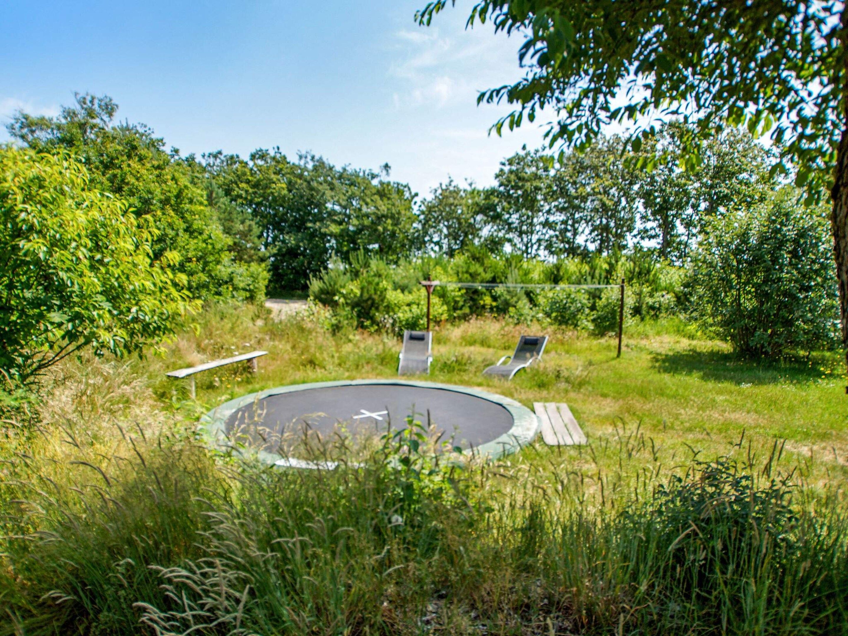 A circular outdoor area with two lounge chairs and a small table, surrounded by grass and trees.