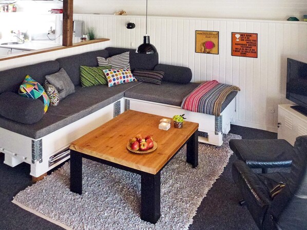 A modern living room with a sectional sofa, a wooden coffee table, and a television.