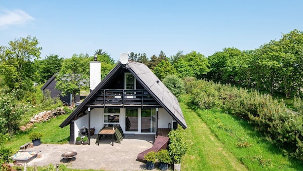 Une maison moderne avec un toit en pente, une terrasse dotée de mobilier d’extérieur et un jardin.