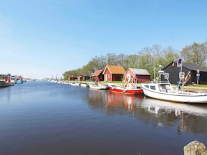 A calm waterway with boats docked, red and white buildings, and a clear sky.