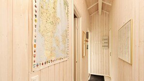 Un pasillo con paredes de madera, un mapa grande y una puerta que da a otra habitación.