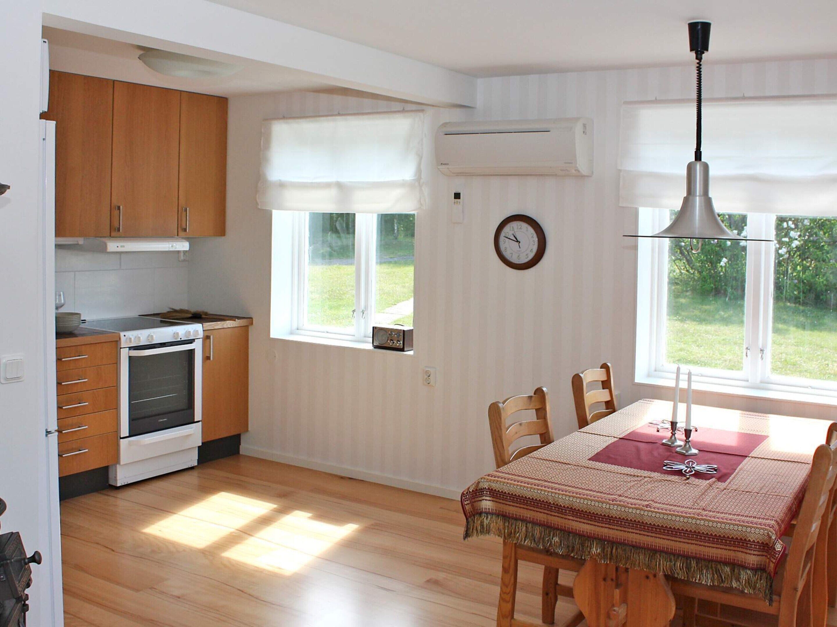 Una cocina con armarios de madera, una estufa y una zona de comedor con mesa y sillas.