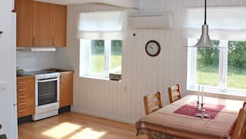 Una cocina con armarios de madera, una estufa y una zona de comedor con mesa y sillas.