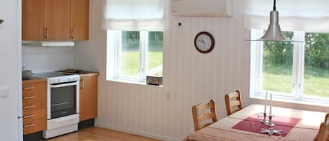 Una cocina con armarios de madera, una estufa y una zona de comedor con mesa y sillas.