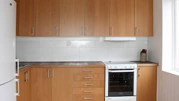 Una cocina con armarios de madera, una estufa blanca y una ventana.