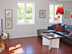 A living room with a leather sofa, a coffee table, and framed pictures on the walls. - Holiday Home in Söderåkra (Soderakra)