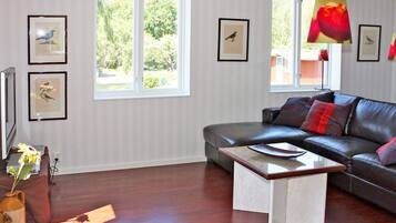 A living room with a sofa, a coffee table, and framed bird pictures on the wall.