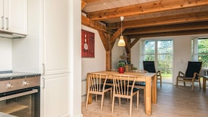 A kitchen with white cabinets and a wooden ceiling, a dining area with a table and chairs, and large windows. - 4 Star Holiday Home in Blavand (Blavand)