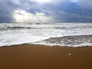A beach with waves, a cloudy sky, and a visible horizon. - 4 Star Holiday Home in Blavand (Blavand)