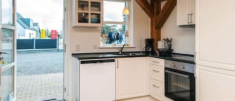 A kitchen with white cabinets, a built-in oven, and a window with a view of people outside.