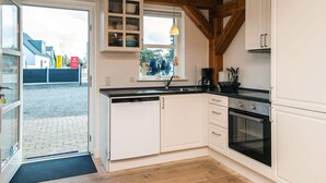A kitchen with white cabinets, a built-in oven, and a window with a view of people outside.