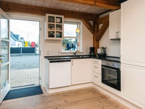 A kitchen with white cabinets, a built-in oven, and a window with a view of people outside.