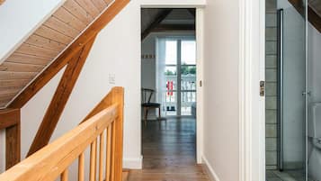 A wooden staircase leading to a room with a glass shower.