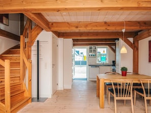 A wooden interior with a staircase, a dining area, and a kitchen visible through an open door. - 4 Star Holiday Home in Blavand (Blavand)