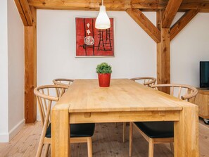 A dining area with a wooden table, six chairs, a potted plant, and a red abstract painting on the wall. - 4 Star Holiday Home in Blavand (Blavand)