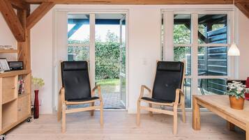Una habitación con dos sillas de madera, una mesa de madera y una estantería.