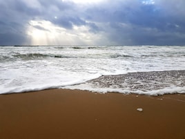 A beach with waves and a cloudy sky.