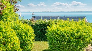 Ein Garten mit ordentlich geschnittenen Büschen und einer Solaranlage im Hintergrund.