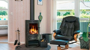 Ein gemütliches Zimmer mit Kaminofen, Ledersessel und Blick ins Grüne.