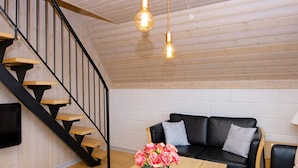 A modern interior with a wooden staircase, a black leather sofa, and a wooden table with a vase of flowers. - 6 Person Holiday Home in Aabenraa-by Traum (Aabenraa)