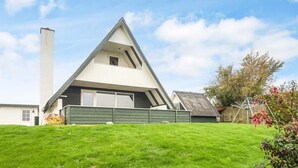 A modern house with a sloped roof, a large chimney, and a well-maintained lawn. - 6 Person Holiday Home in Aabenraa-by Traum (Aabenraa)