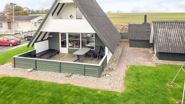 A modern house with a sloped roof, a patio area with outdoor furniture, and a view of the surrounding landscape. - 6 Person Holiday Home in Aabenraa-by Traum (Aabenraa)