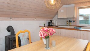 A cozy kitchen with wooden walls, a wooden table, a stove, and a hanging light fixture. - 6 Person Holiday Home in Aabenraa-by Traum (Aabenraa)