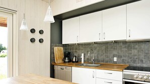 A modern kitchen with white cabinets, a wooden countertop, a built-in oven, and a coffee maker. - Eco-friendly Retreat in Nature - By Traum Ferienwohnungen (Fjerritslev)