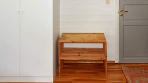 Een kamer met een houten bankje, een witte kast en een grijze deur.