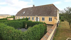 A two-story house with a tiled roof, a small garden with hedges, and a paved pathway leading to the entrance. - Contemporary Apartment in Faaborg near Sea (Faaborg)