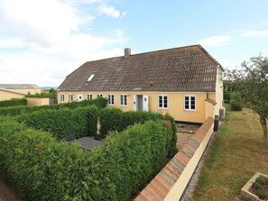 A two-story house with a tiled roof, a small garden with hedges, and a paved pathway leading to the entrance. - Contemporary Apartment in Faaborg near Sea (Faaborg)