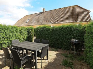An outdoor patio with a table and chairs, a barbecue grill, and a hedge. - Contemporary Apartment in Faaborg near Sea (Faaborg)
