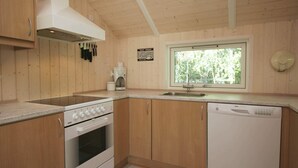 A compact kitchen with wooden cabinets, a stove, a sink, and a dishwasher. - 9 Person Holiday Home in Vaeggerlose-by Traum (Vaeggerlose)