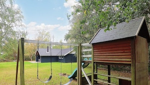 A wooden swing set and a small playhouse in a backyard. - 9 Person Holiday Home in Vaeggerlose-by Traum (Vaeggerlose)