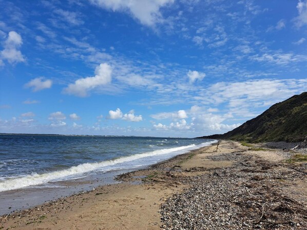 A beach with pebbles, a clear sky, and a distant hill. - Spacious Holiday Home In Struer near Ocean (Struer)