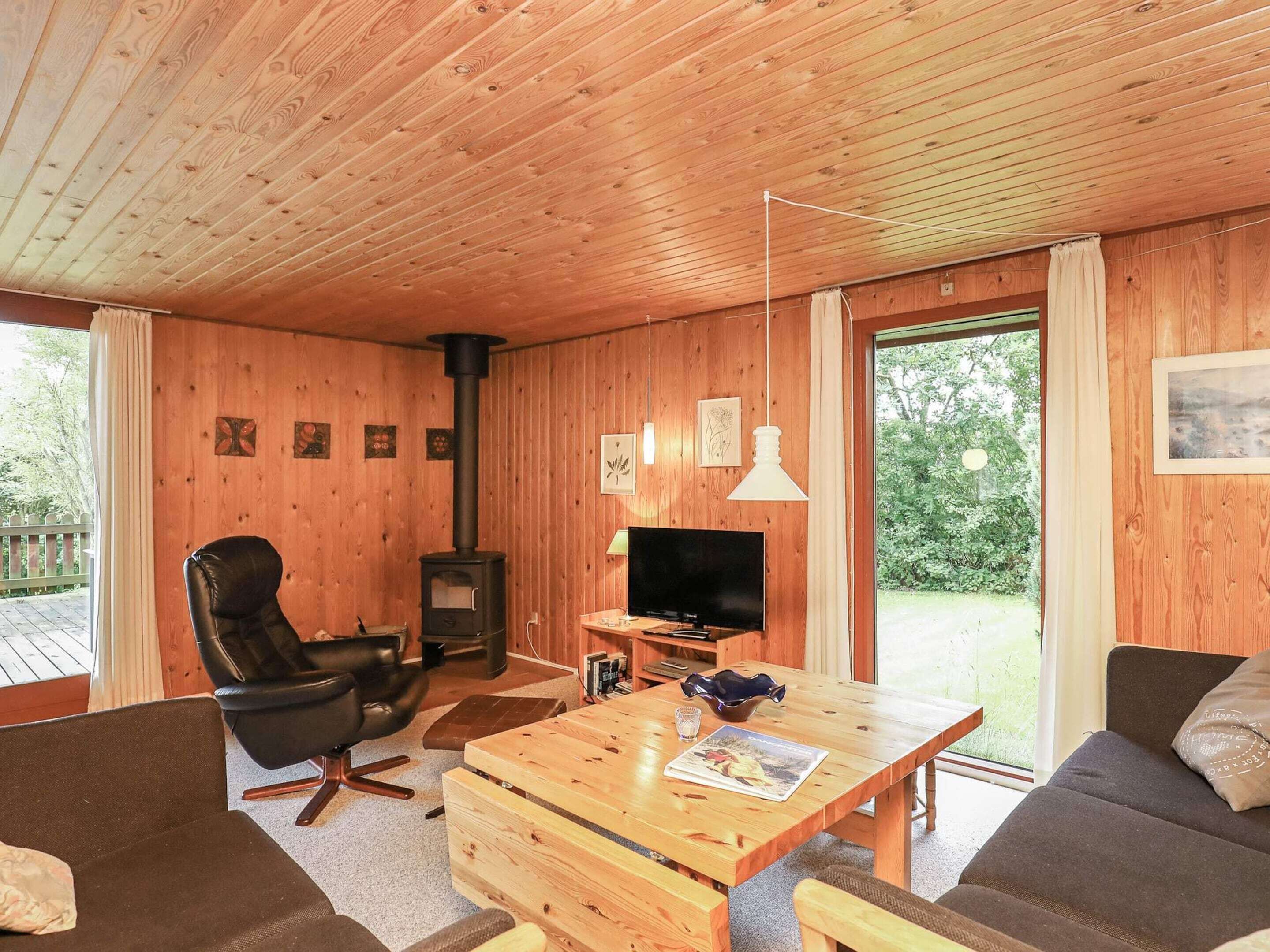 A cozy cabin interior with a wooden interior, a fireplace, a television, and a sofa.