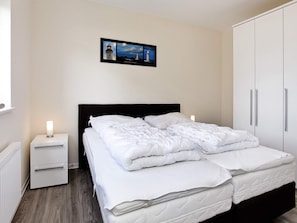 A bedroom with a bed, a nightstand, a wardrobe, and a framed picture on the wall. - Holiday Home in GroÃ Ÿenbrode (Grossenbrode)