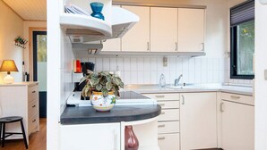 Eine moderne Küche mit weißen Schränken, einer schwarzen Arbeitsplatte und einem Blumentopf.