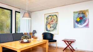 Ein modernes Wohnzimmer mit einem Holztisch, einem schwarzen Ledersessel, einer Couch und zwei Bildern an der Wand.