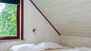 A small, single-bed room with white bedding and a window with a view of green trees. - Peaceful Holiday Home in Ebeltoft near Sea (Ebeltoft)