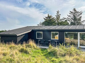 A modern house with a dark exterior, large windows, and a flat roof.