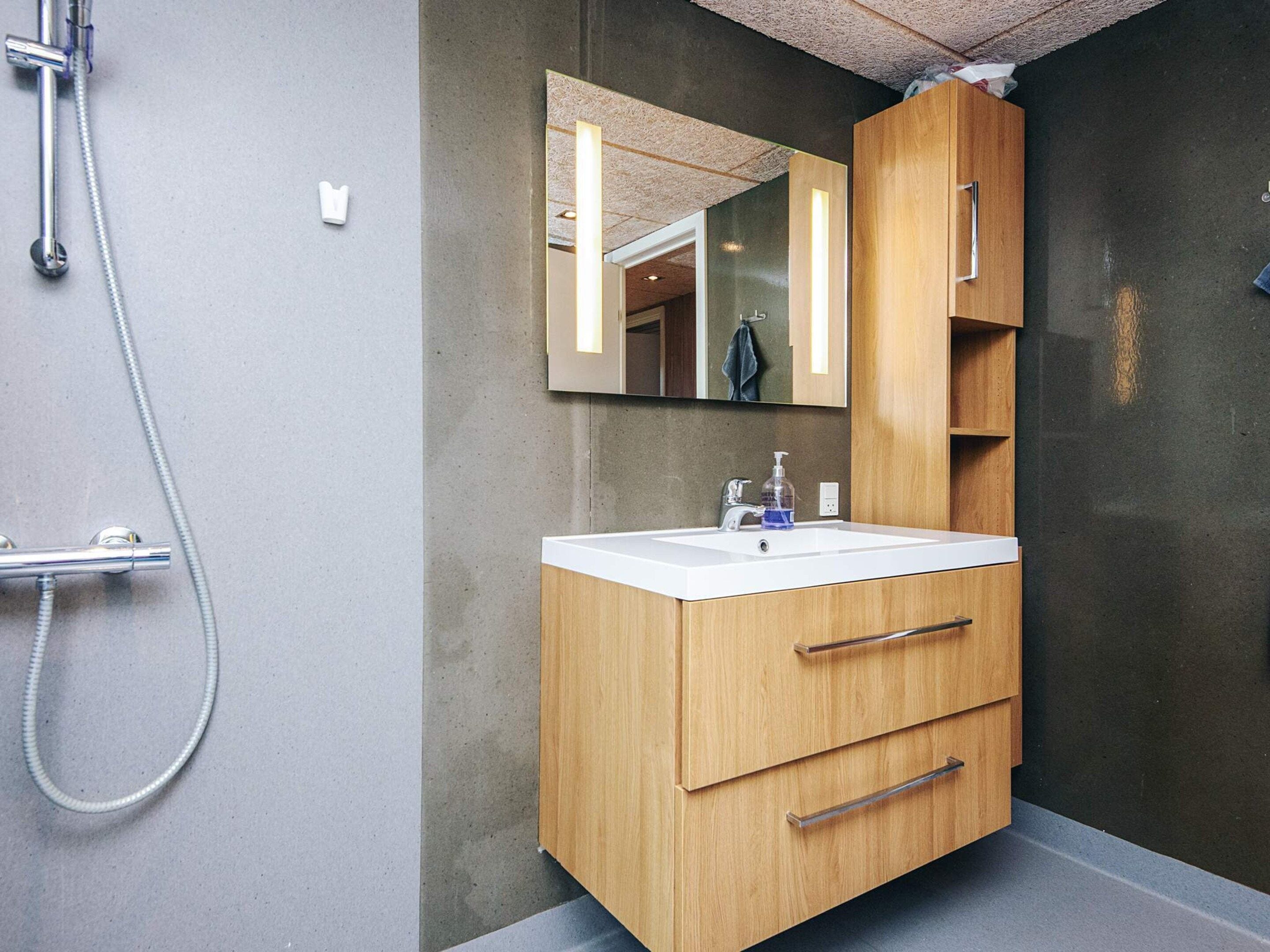 Une salle de bain moderne avec un meuble-lavabo en bois, un grand miroir et une douche.