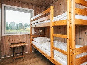 Dormitorio con literas, paredes de madera y ventana con vistas a un paisaje verde.