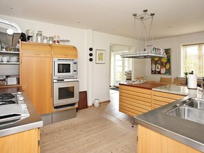 A modern kitchen with a built-in oven, microwave, and stainless steel sink. - 5 Person Holiday Home in Skagen-by Traum (Skagen)