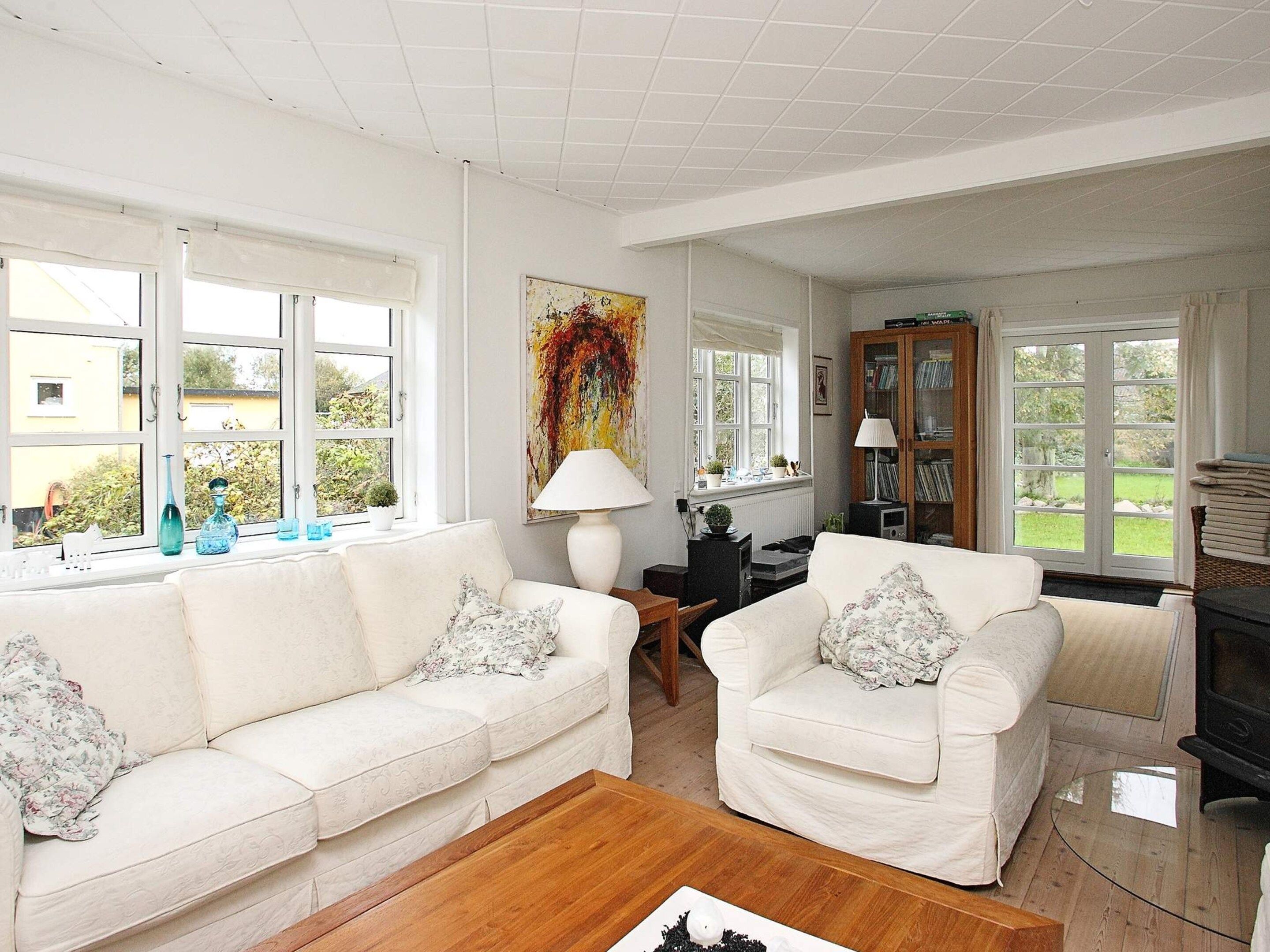 A living room with two white sofas, a coffee table, a fireplace, and a bookshelf.